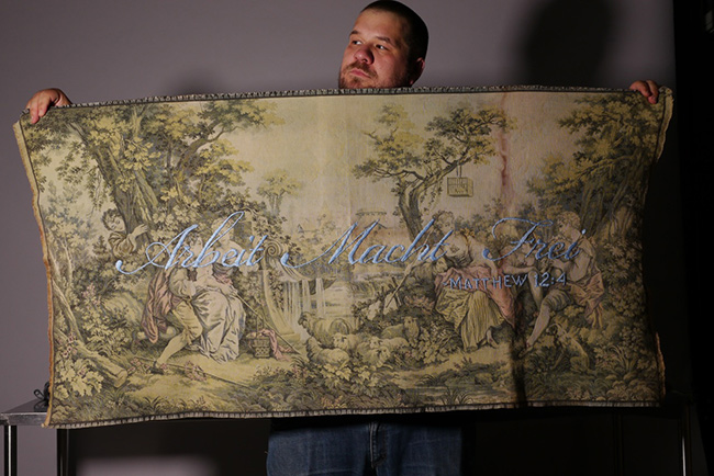 Jason Kreher holding up one of his tapestries